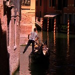 A singing gondolier kicks off wall through the canals of Venice