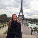 A student studying abroad poses in France with the Eiffel Tower.
