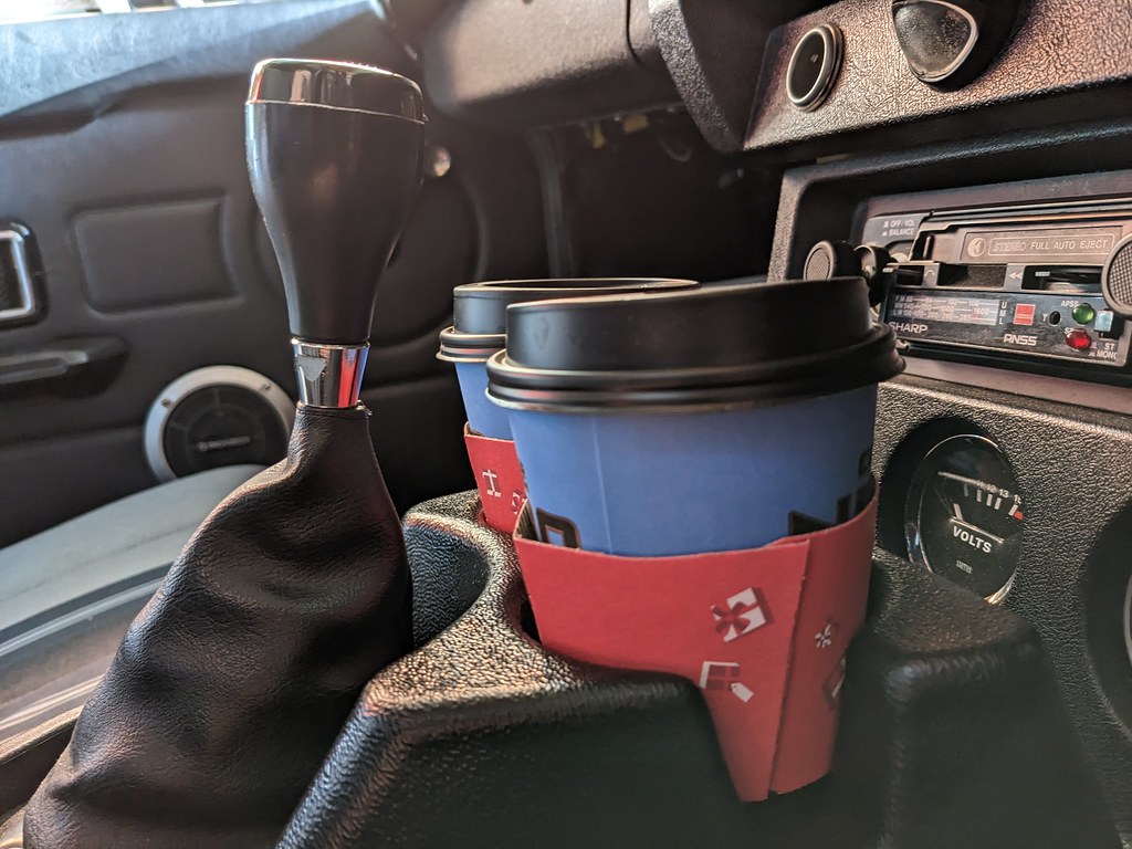 The holder with a couple of Cafe Nero cups in and the gearstick pushed forward. There is maybe a couple of inches of space between them