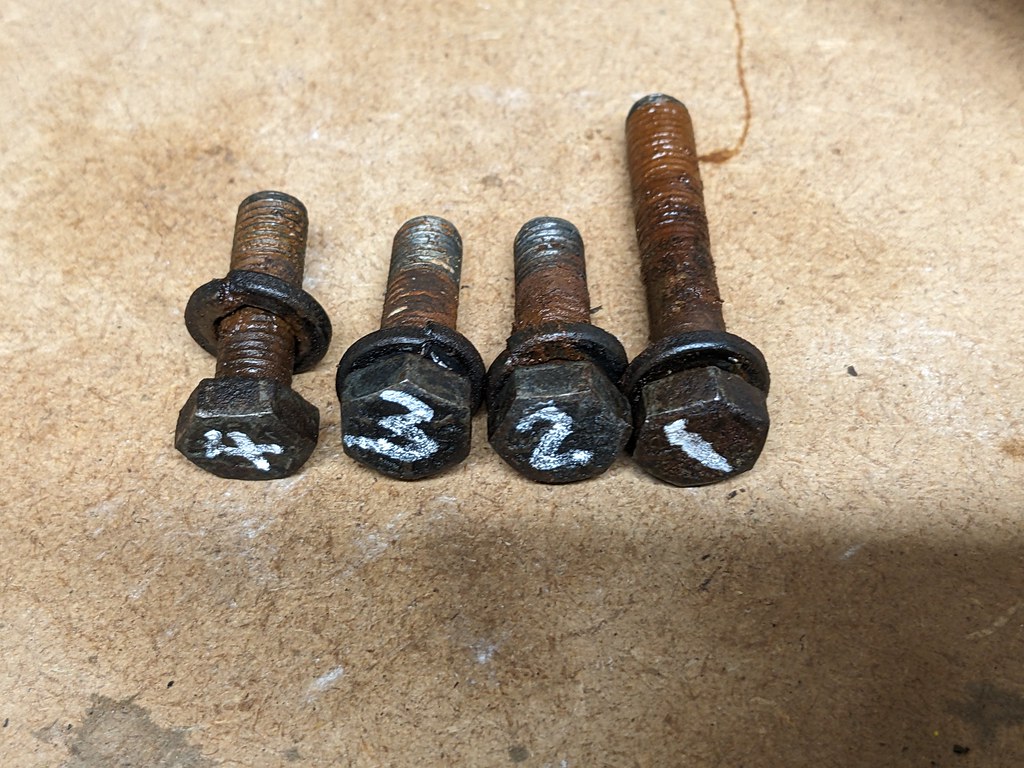 Four bolts, numbered 1 to 4 by a white chalk pen on the head of the bolts. Bolt number one is longer than the others