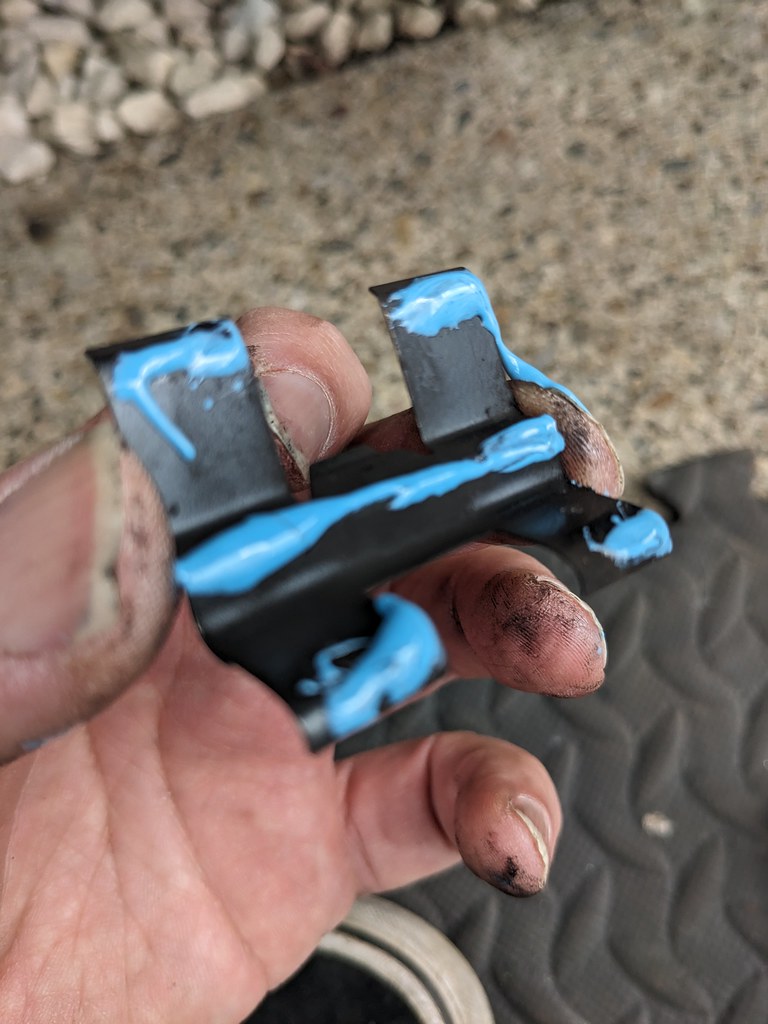 A H-shaped spring clip with blue paste all over it