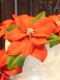 Closeup of hand made red and green sugar poinsettia flowers On Christmas Eve wedding cake